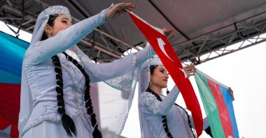 Two Azerbaijani women in local clothes raise Turkish and Azerbaijani flags as a part of Nevruz celebrations, Ankara, Türkiye, March 21, 2021. (Shutterstock Photo)