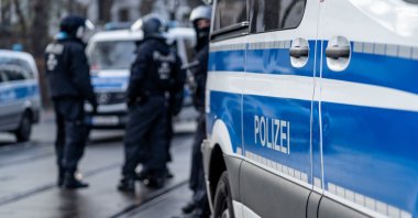 German police car from Berlin is in the focus and in the blurry background are several riot police cops standing on the street and waiting for action on a demonstration, Dec. 13, 2020. (Shutterstock File Photo)