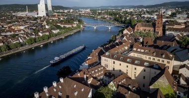 An aerial view shows a barge sailing on the Rhine River with the towers (L) housing the headquarters of Swiss pharma giant Roche and the cathedral (R), ahead of the 2025 Eurovision Song Contest, Basel, Switzerland, May 3, 2025. (AFP Photo)