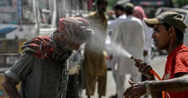A volunteer sprays water on a passerby&#039;s head to cool off on a hot summer day along a road amid the ongoing heat wave, Karachi, Pakistan, April 21, 2025. (AFP Photo)