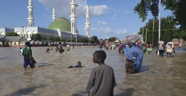 People walk through floodwaters following a dam collapse, Maiduguri, Nigeria, Sept. 10, 2024. (AP Photo)