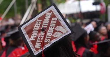 A Harvard University graduate wears a cap written "Protect International Students" as she protests Donald Trump&#039;s move to ban international students, Cambridge, U.S., May 28, 2025. (AA Photo)